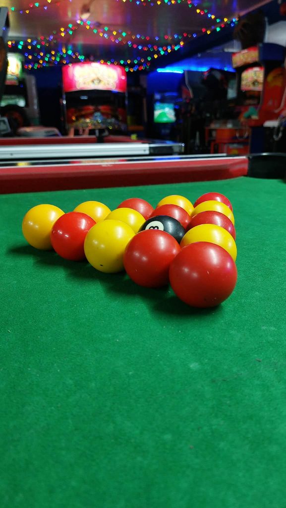Racked pool balls on the green baize of the arcade pool table