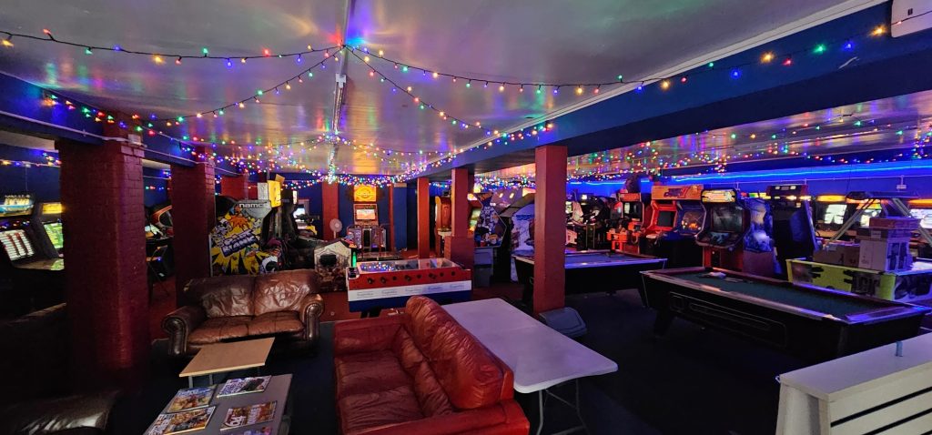 Wide view of the arcade floor with seating, pool table and cabinets